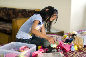 Child playing with a variety of dolls. 